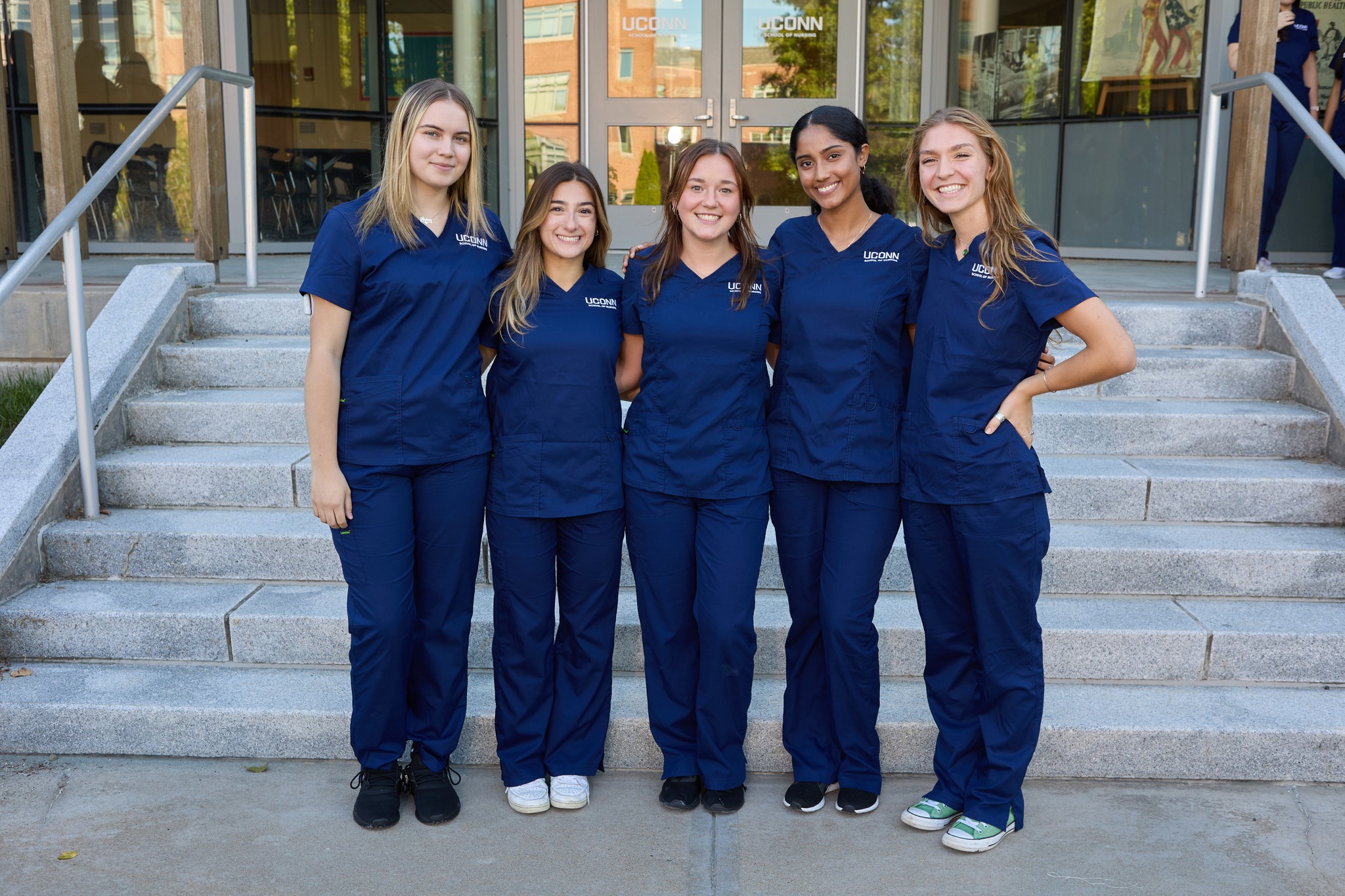 5 nursing students in scrubs smiling outside Storrs Hall